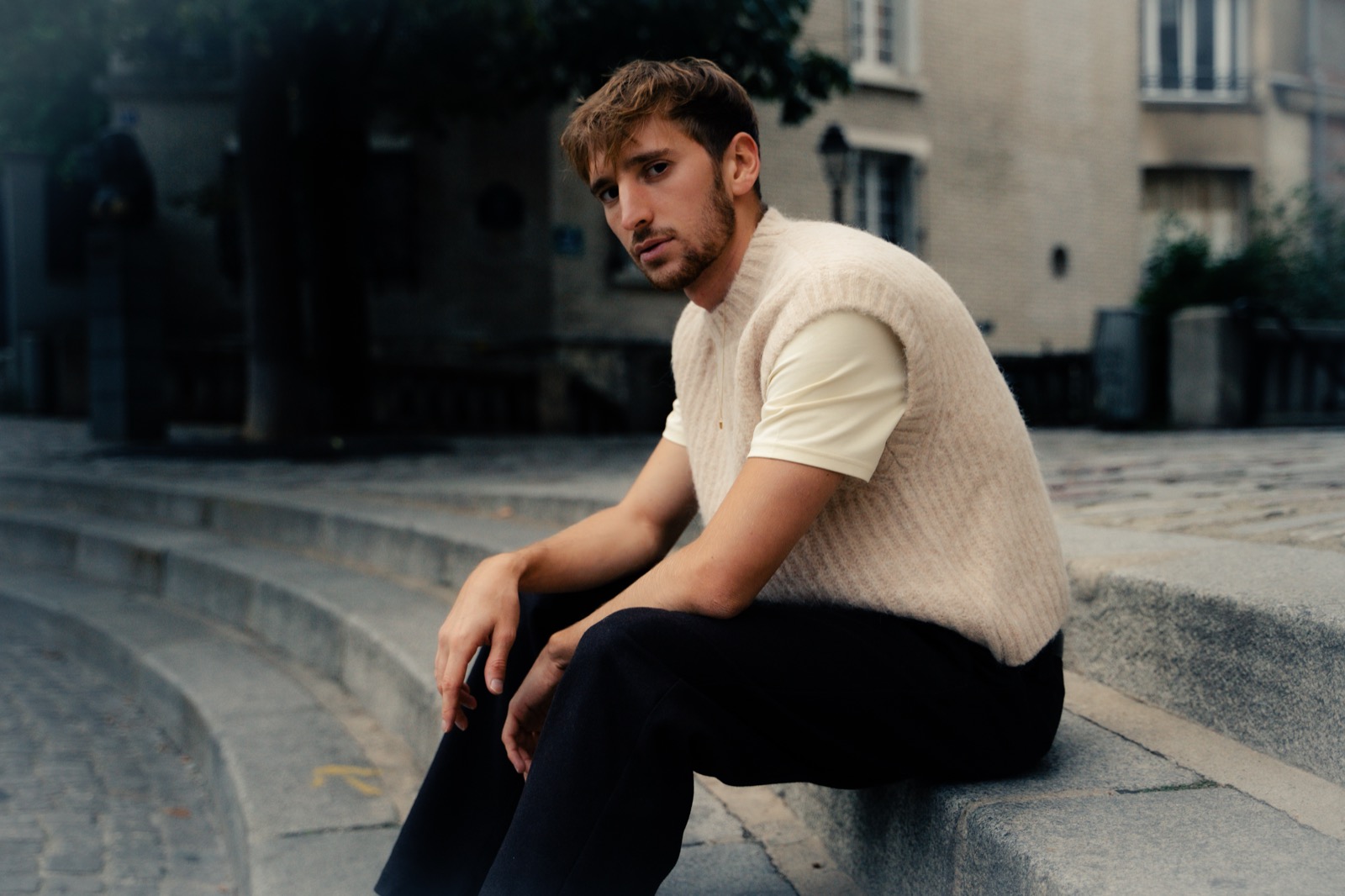 Mathis Riviere assis sur des marches de pierre, dans une rue de Paris